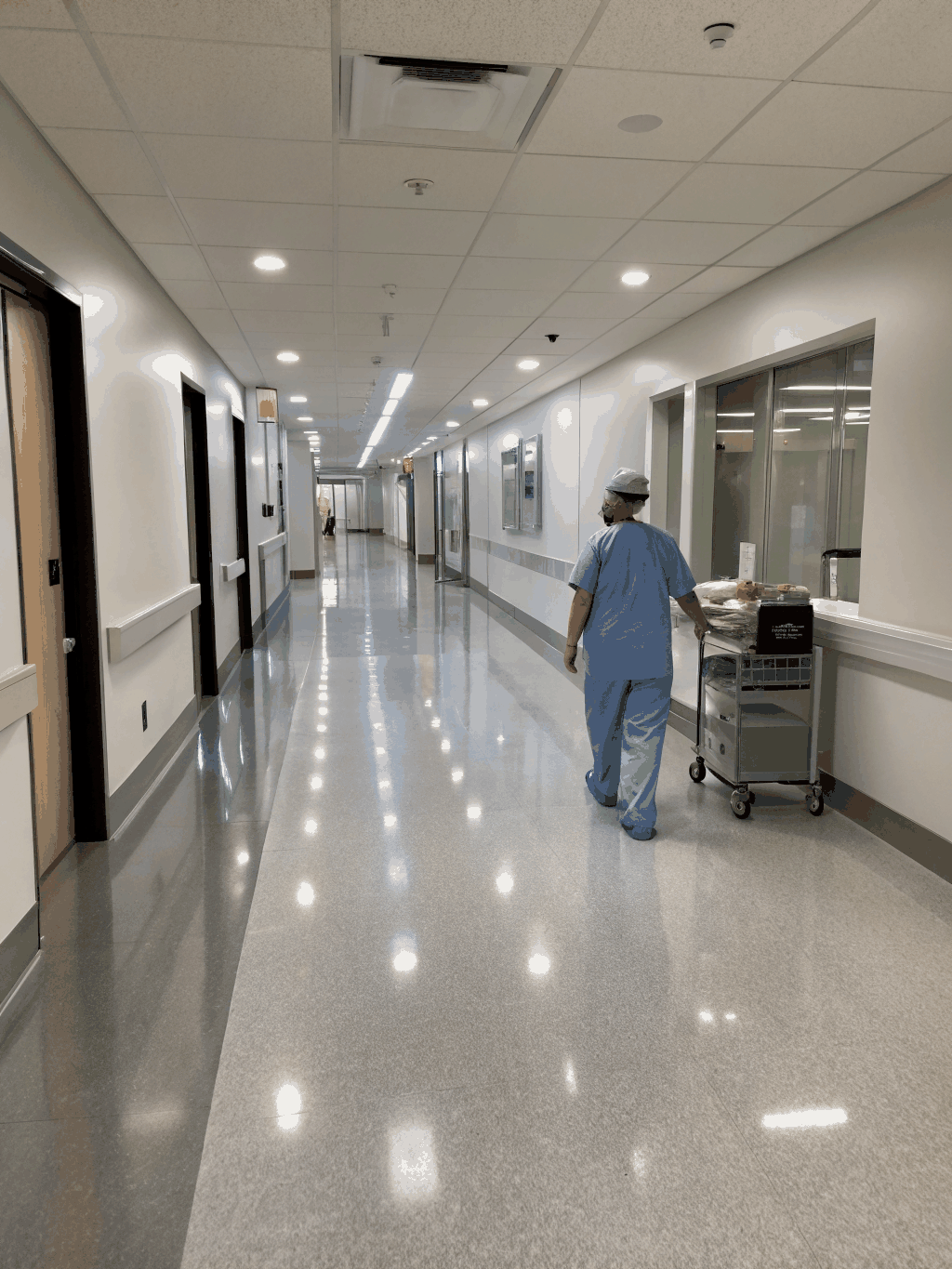 Dramatic monochrome hospital hallway with deep shadow falloff and single-source key lighting